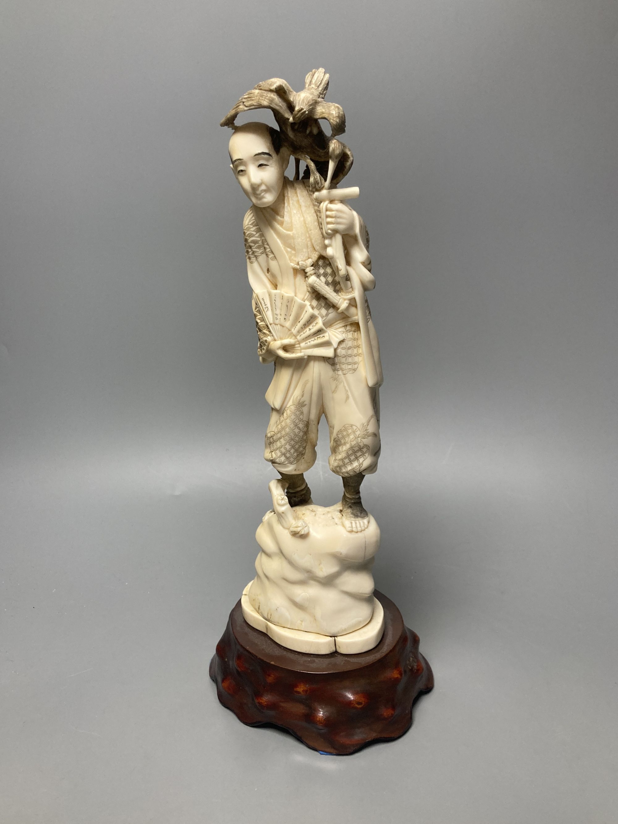 A Japanese walrus ivory okimono of a cormorant fisherman, early 20th century, overall height 34cm